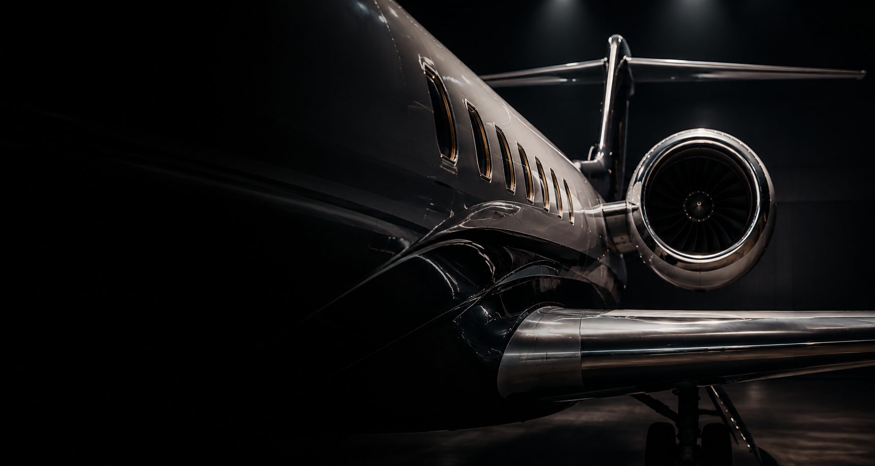 Close-up detail of a business jet fuselage and engine in dramatic light